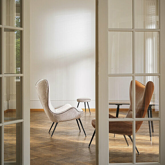 two Contessa high-back chairs in white cover and leather upholstery behind double doors with glass inserts 
