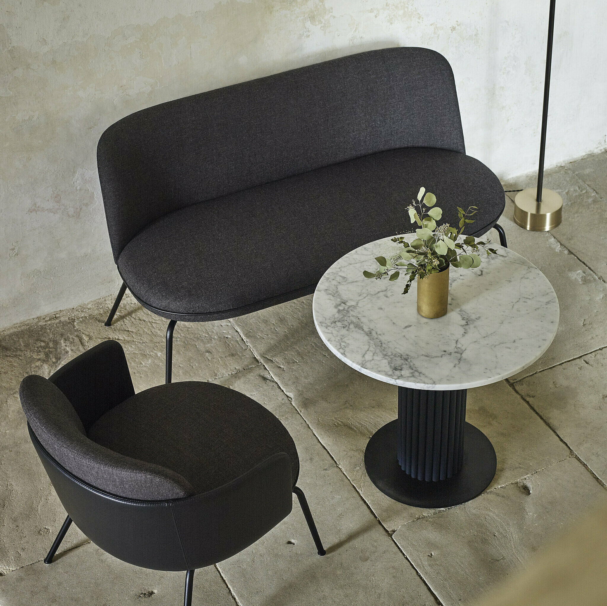 Miles Table mit weißer Marmorplatte und dunkelblauer Tischsäule in Leder. Der Tisch steht zwischen den Merwyn Lounge Sofa und dem Merwyn Lounge Fauteuil 