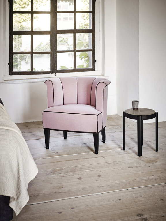 pink Alleegasse armchair in front of brown window in historical building