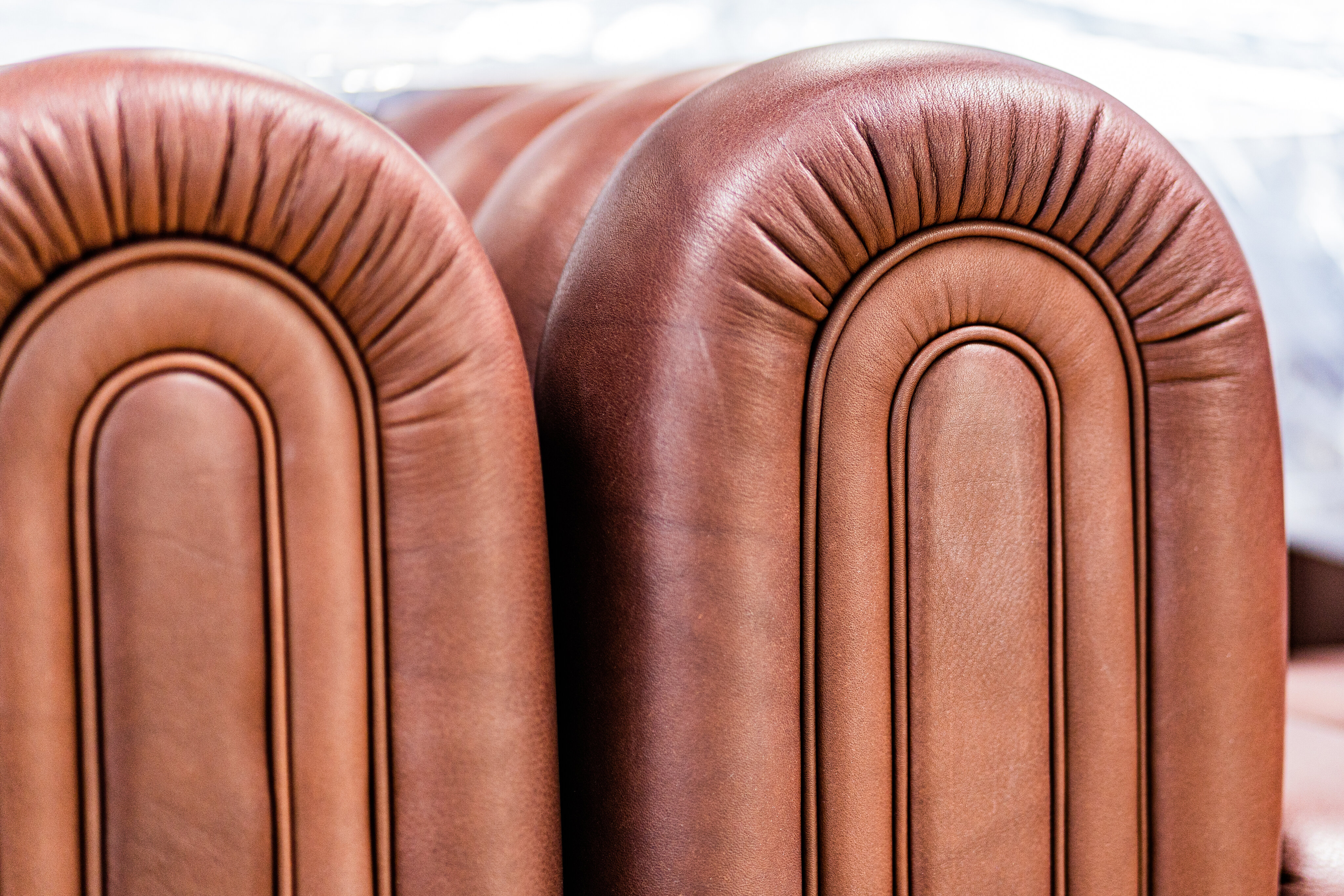 Detail of the arched stitched armrest of the Club 1910 series in brown leather