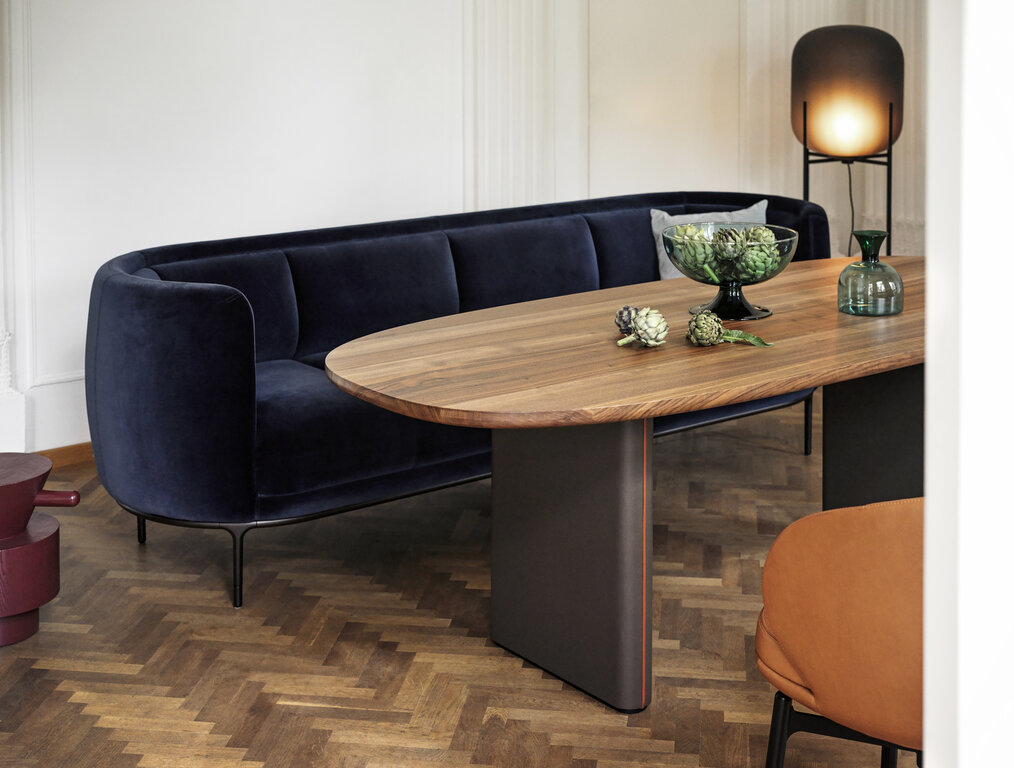 Vuelta sofa with dark blue velvet cover in front of Merwyn FD table with wooden top and Vuelta FD chair with cognac leather cover