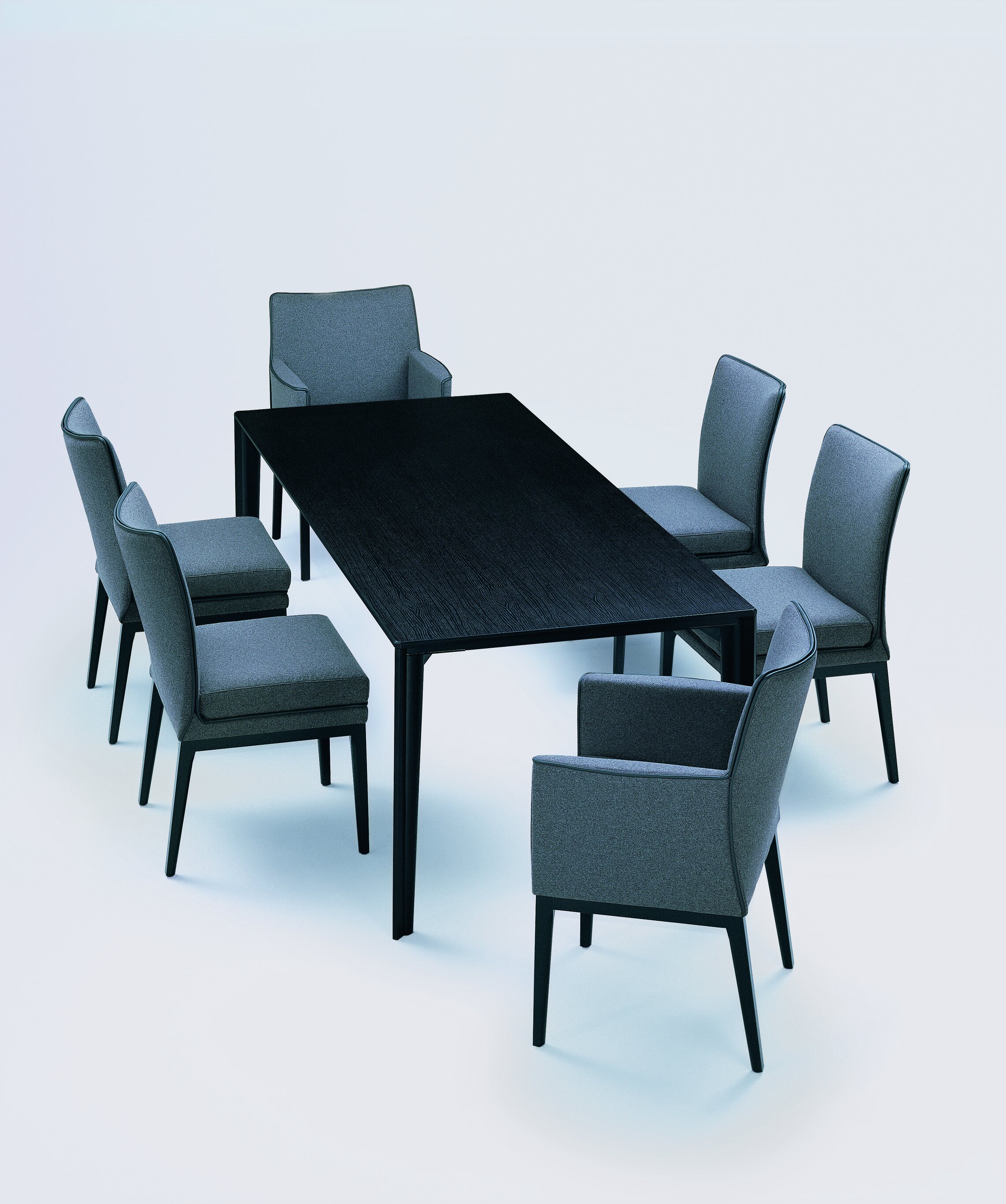 mehrere dunkelgrau bezogene Sedan Stühle gruppieren sich um schwarzen Tisch