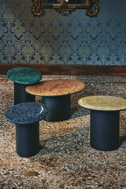 four oval Antilles side tables with different marble tops on terrazzo floor in front of silk wallpaper