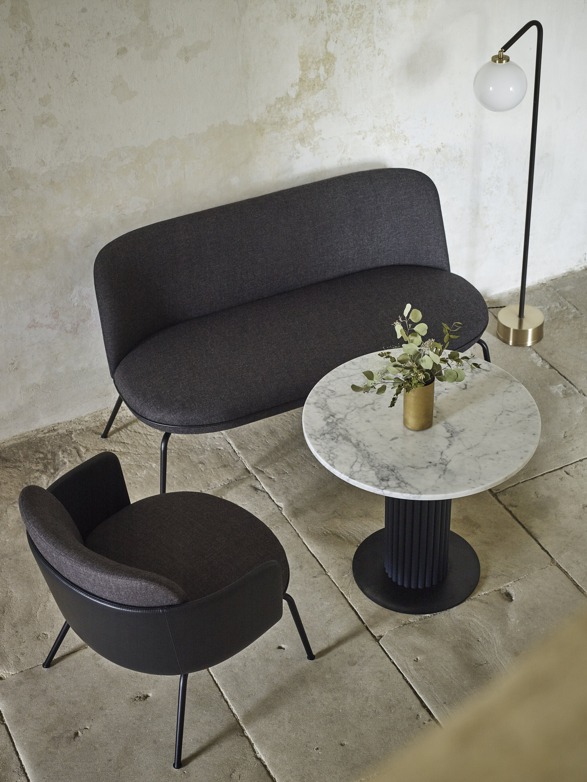 Miles Table mit weißer Marmorplatte und dunkelblauer Tischsäule in Leder. Der Tisch steht zwischen den Merwyn Lounge Sofa und dem Merwyn Lounge Fauteuil 